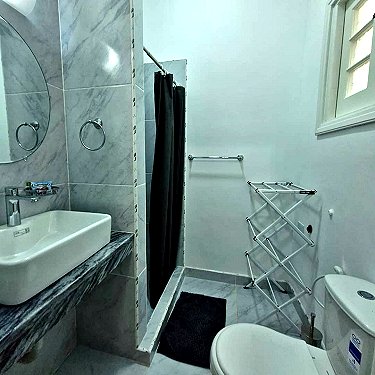 Ba&ntilde;o con inodoro, lavabo y ducha al fondo